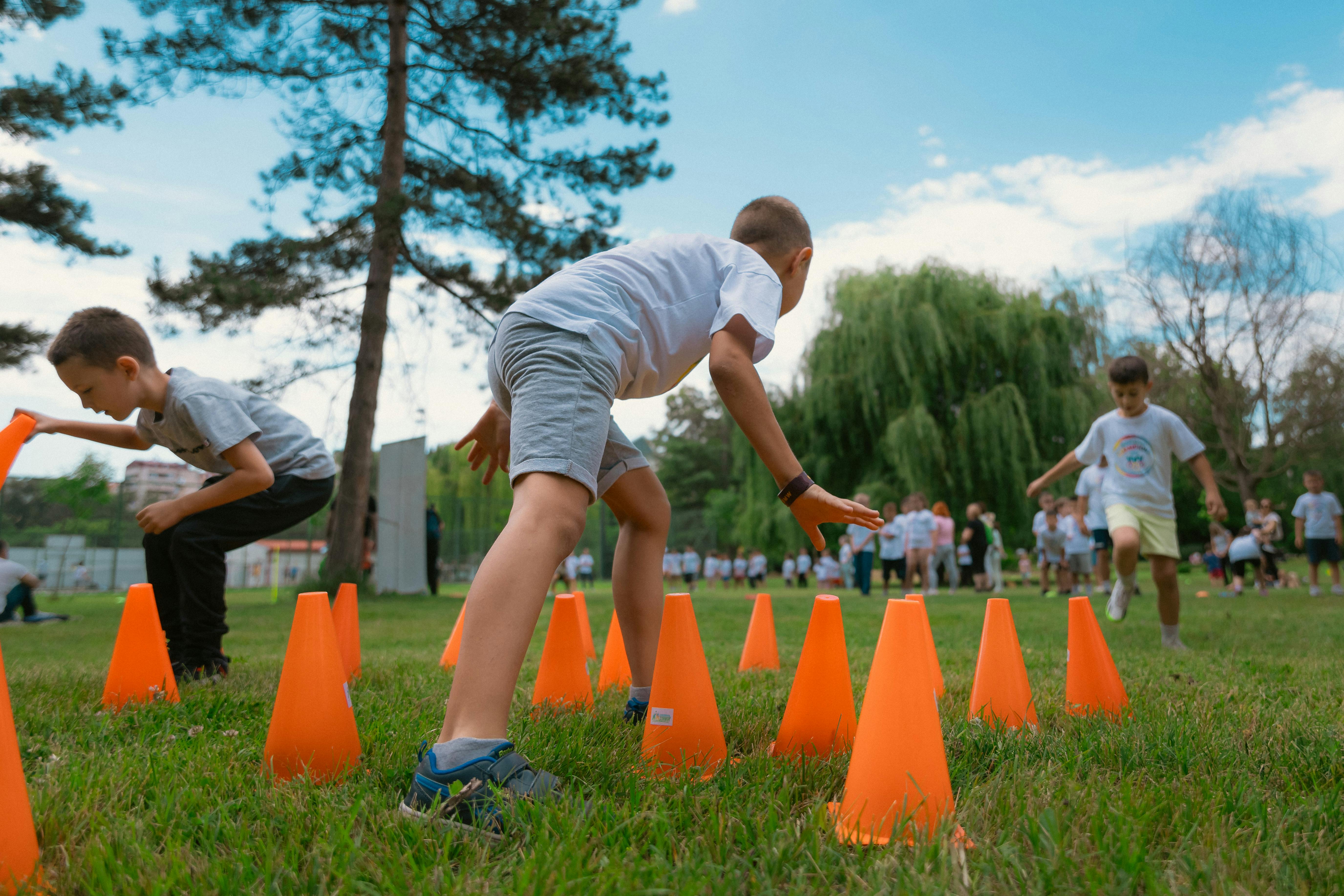 Children running through an orange cone obstacle course on grass